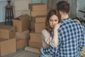 A man and woman hugging while packing up the belongings of a passed loved one.