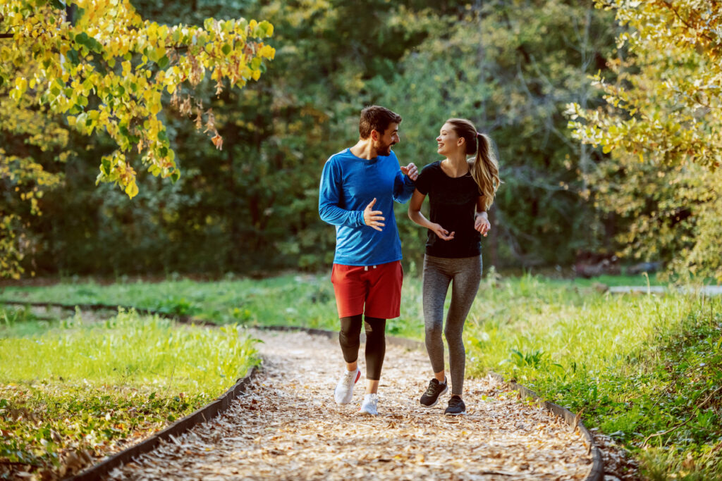 A man and woman walk together on an outdoor trail to stay fit.