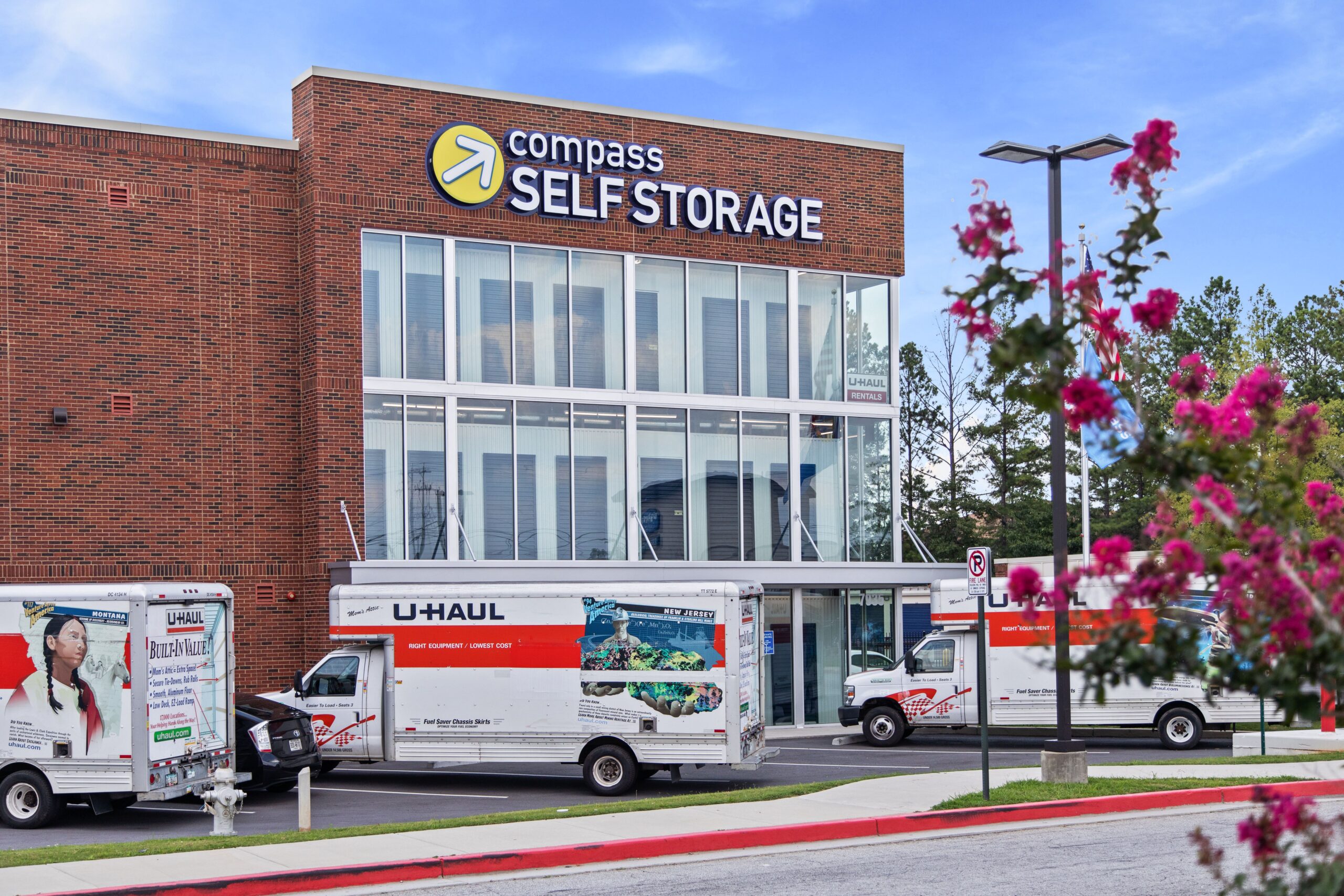 Moving trucks parked outside of Compass Self Storage.