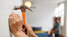 A woman hammering a nail into the wall of her new house.