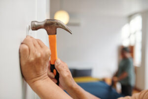 A woman hammering a nail into the wall of her new house.