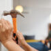 A woman hammering a nail into the wall of her new house.