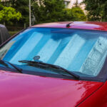 A red car parked outside with a sunshield inside its cabin.