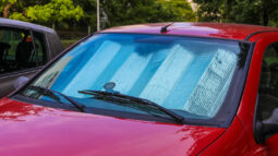 A red car parked outside with a sunshield inside its cabin.