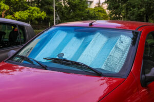 A red car parked outside with a sunshield inside its cabin.