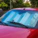 A red car parked outside with a sunshield inside its cabin.