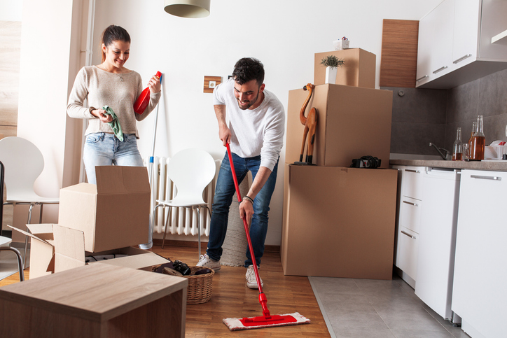 A man and woman mopping the floor of their new home.