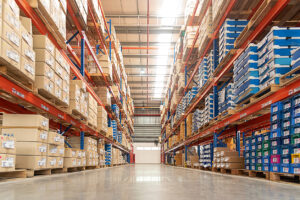 A wide warehouse storage aisle with tall shelving units and neatly organized boxes.