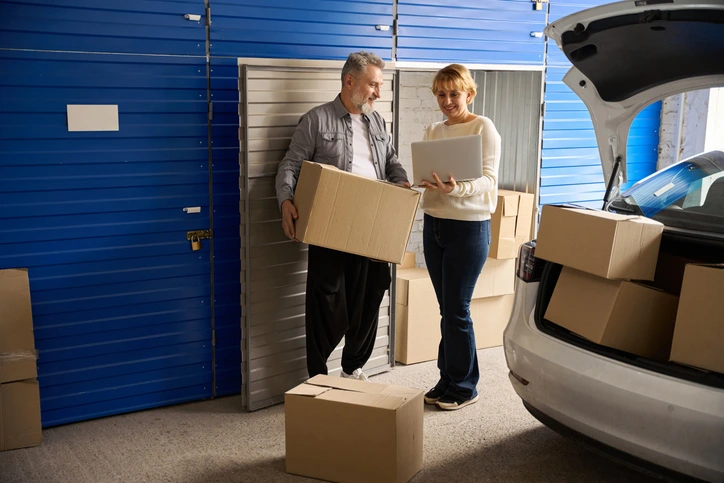 Business owners moving inventory boxes between a vehicle and a storage unit.