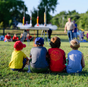 Four kids who are part of Mansfield Cub Scout Pack 1993 watch a handmade rocket launch