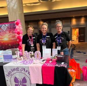 The team of Loving Arms Cancer Outreach stands behind a table, ready to inform others about their non-profit organization